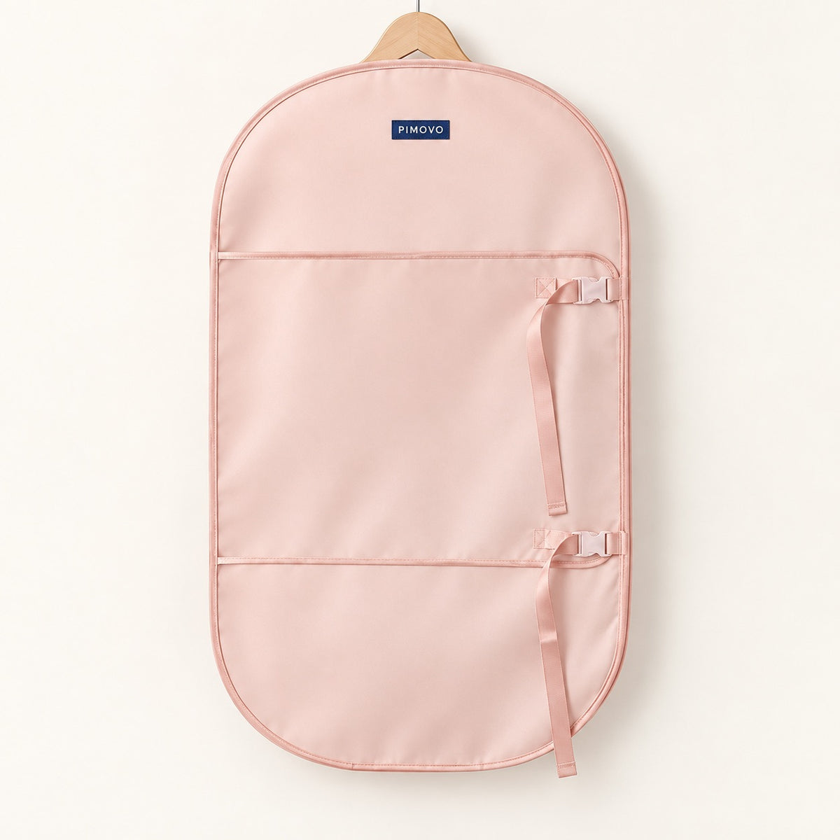 PIMOVO branding concept: the open pink wardrobe wrap on a wooden hanger against a cream background.